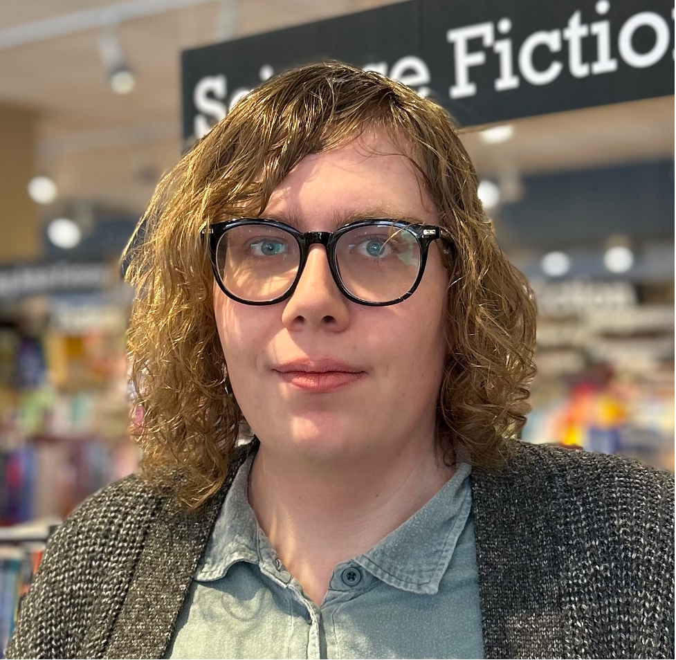 Student research assistant Julie Carr is a white trans woman. She has light brown hair and large round glasses and she is looking straight at the camera visible from the shoulders up.