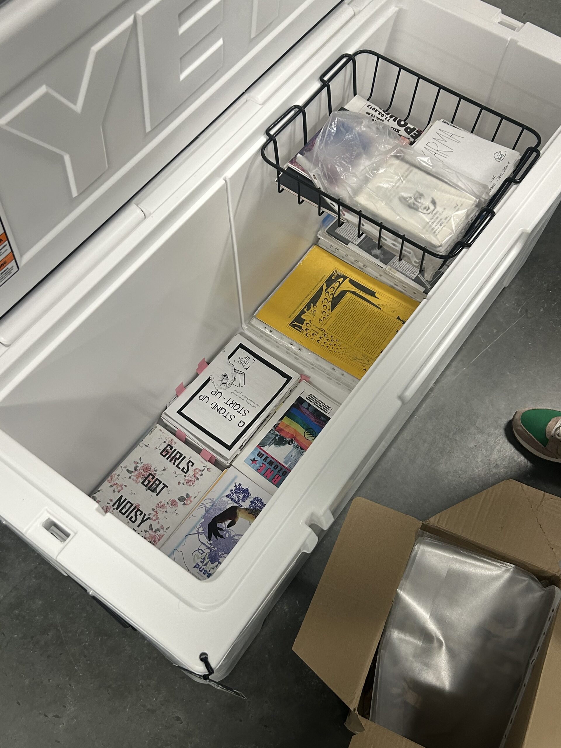 A collection of zines in a large cooler for preservation.